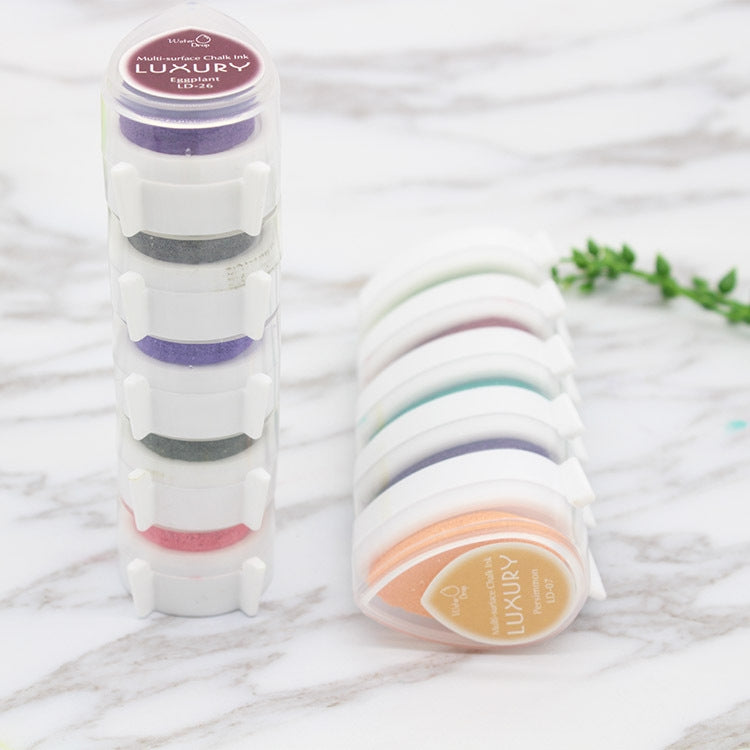 Stacked droplet-shaped ink pads with round lids in purple and other colors