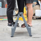 Gray folding step ladder stool with two steps standing on concrete