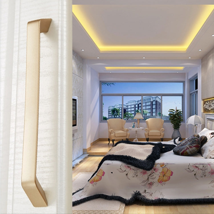 Gold cabinet door pull handle, long curved bar mounted on a vertical panel