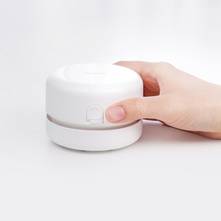 White round desktop mini cleaner with lid tab, held by a hand