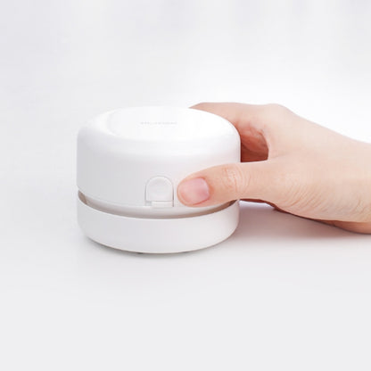 White round desktop mini cleaner with lid tab, held by a hand