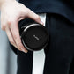 Mini desktop vacuum cleaner held in hand, round black top with NUSIGN logo
