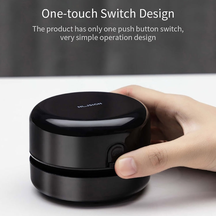 Black mini desktop cleaner with one-touch button, hand pressing the front control