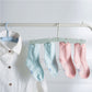 Foldable clothes hanger drying rack with four clips holding pastel socks on a bar