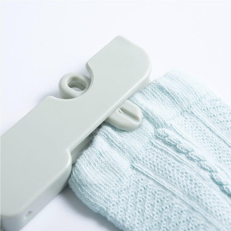 Light green hanger clip holding light blue fabric with curved attachment hook