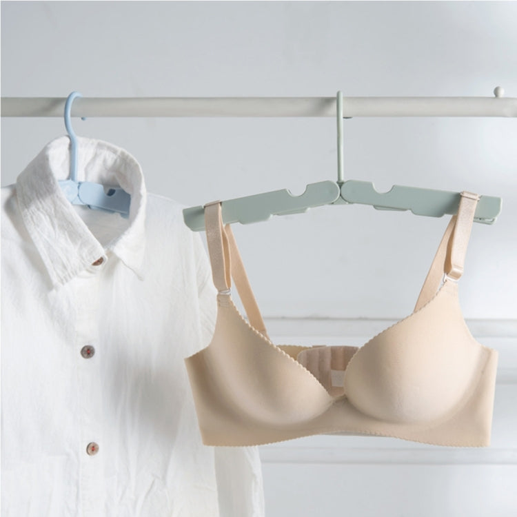 Light green foldable clothes drying hanger rack hanging a bra and shirt on a bar