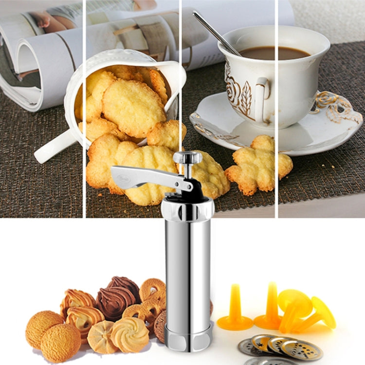 Cookie press with baked cookies and decorative discs on a table near a cup