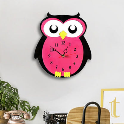 Owl-shaped wall clock with pink body, black wings, yellow beak, and quiet hands