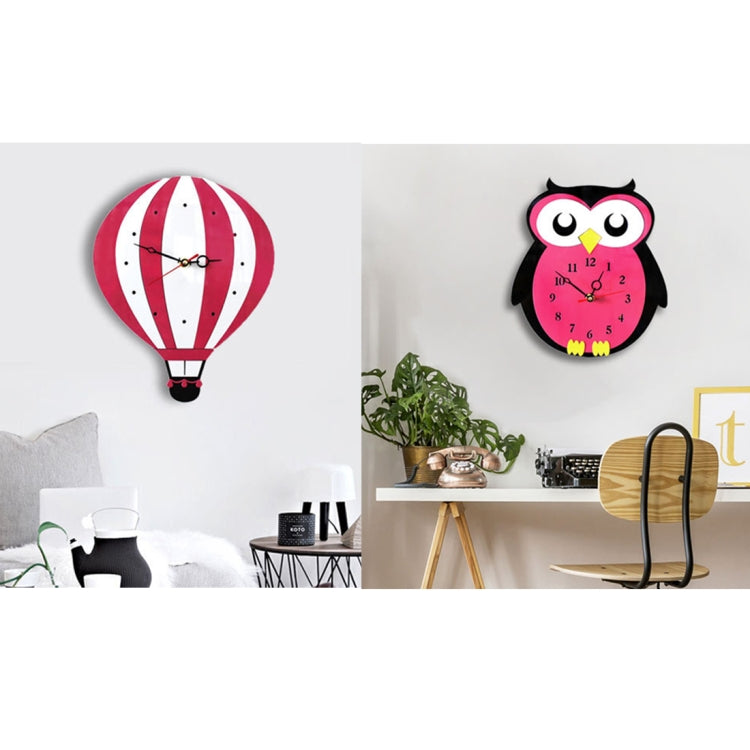 Owl-shaped pink and black wall clock on a wall above a console table with decor