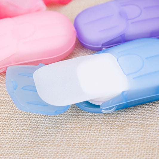 Blue hinged travel case with white mini soap paper strip, pastel pink and purple cases