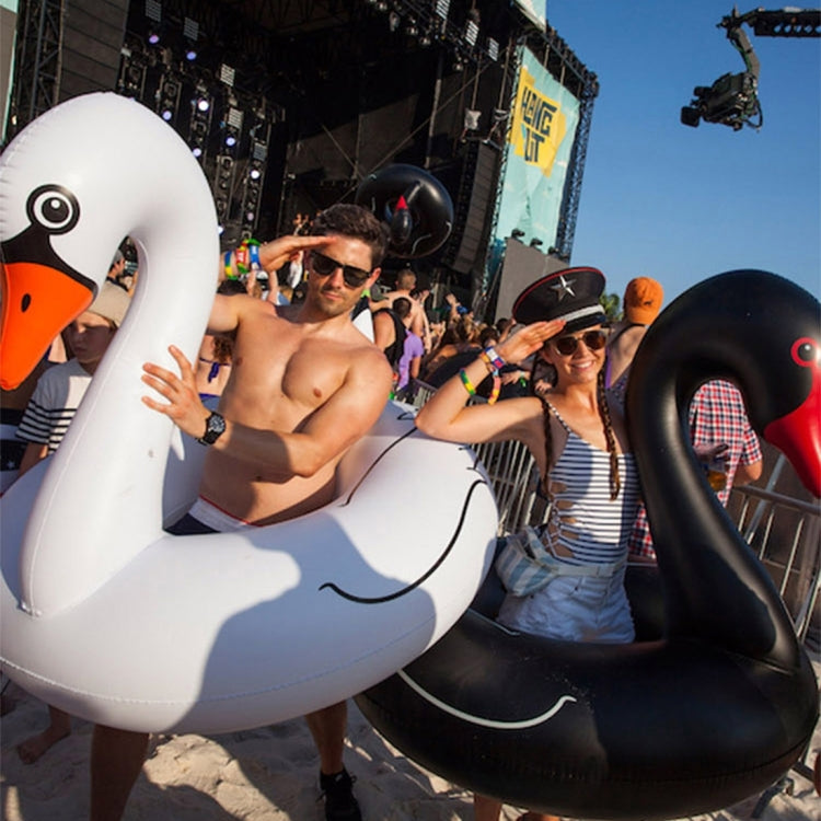 Black swan inflatable pool ring with red beak, next to a white swan ring