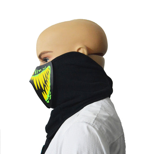 Black face-covering mask with green/yellow glowing mouth design, viewed from the side
