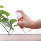 Portable transparent spray bottle with white mist pump, held in hand