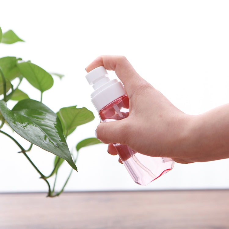 Portable transparent spray bottle with white mist pump, held in hand
