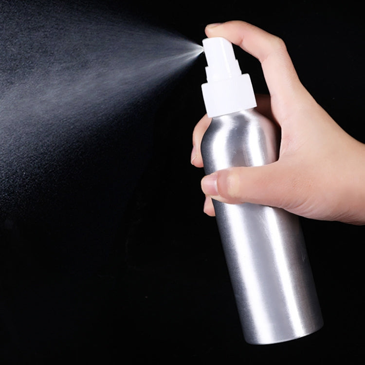 Hand holding aluminum fine-mist spray bottle releasing mist from nozzle
