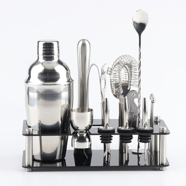 Stainless steel cocktail shaker tools set on black acrylic base, assorted bar accessories