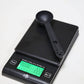 Black coffee cleaning measure spoon resting on a digital kitchen scale