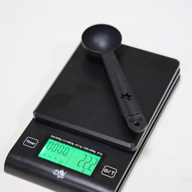 Black coffee cleaning measure spoon resting on a digital kitchen scale