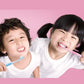 Two children brushing teeth holding pink and blue soft toothbrushes