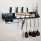 Black wall-mounted kitchen rack with hooks, two cups, and countertop condiment holders