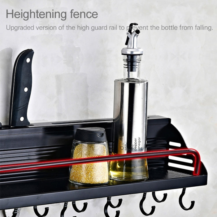 Black condiment rack with raised guard rail holding bottles and kitchen tools