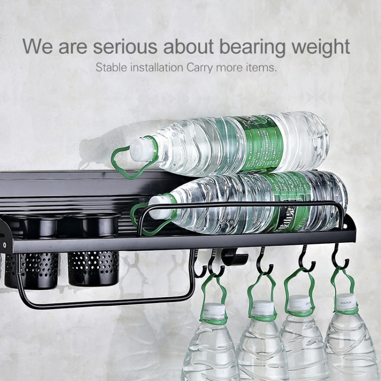 Black wall-mounted rack holding stacked water bottles and items on hanging hooks