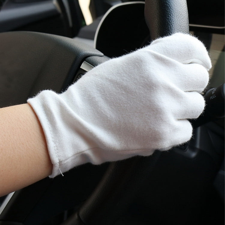 White thin cotton work gloves worn while gripping a steering wheel