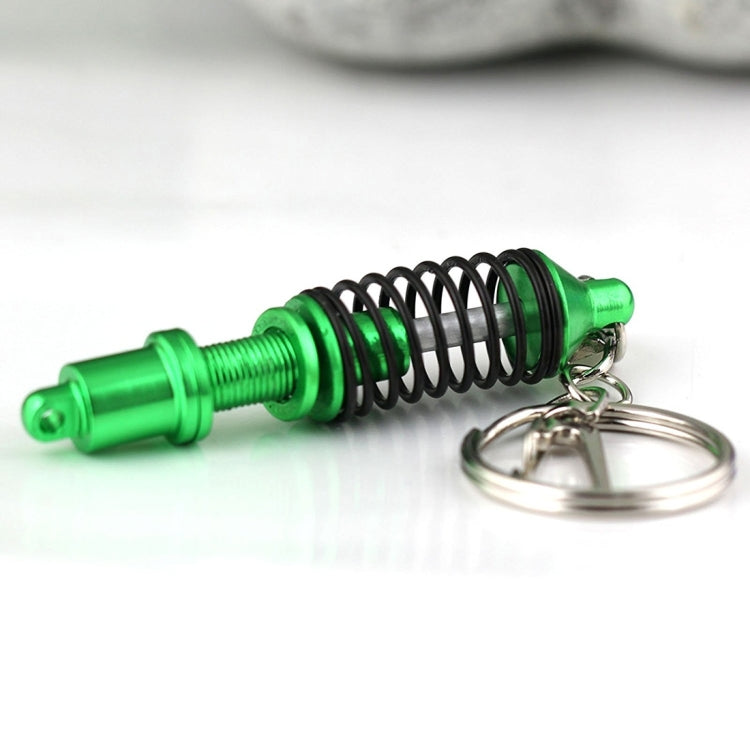 Green and black shock absorber keychain with silver key ring, angled view