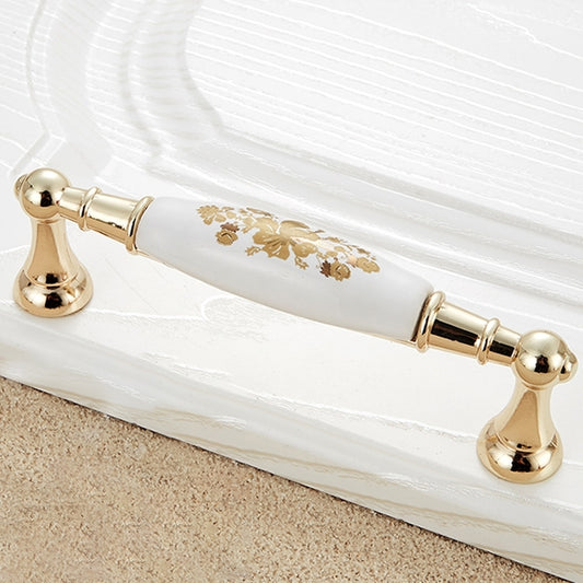 Gold cabinet drawer handle with white ceramic center and decorative floral strip