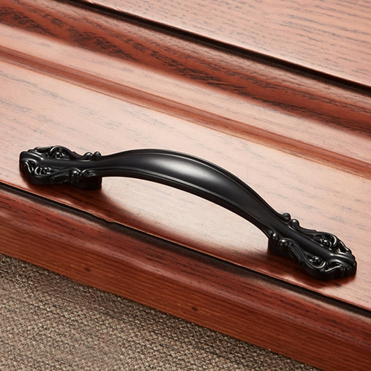 Black zinc alloy cabinet handle with ornate end scrolls and curved bar