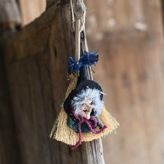 Witch broom hanging ornament with gray-haired doll, blue accents, and straw broom