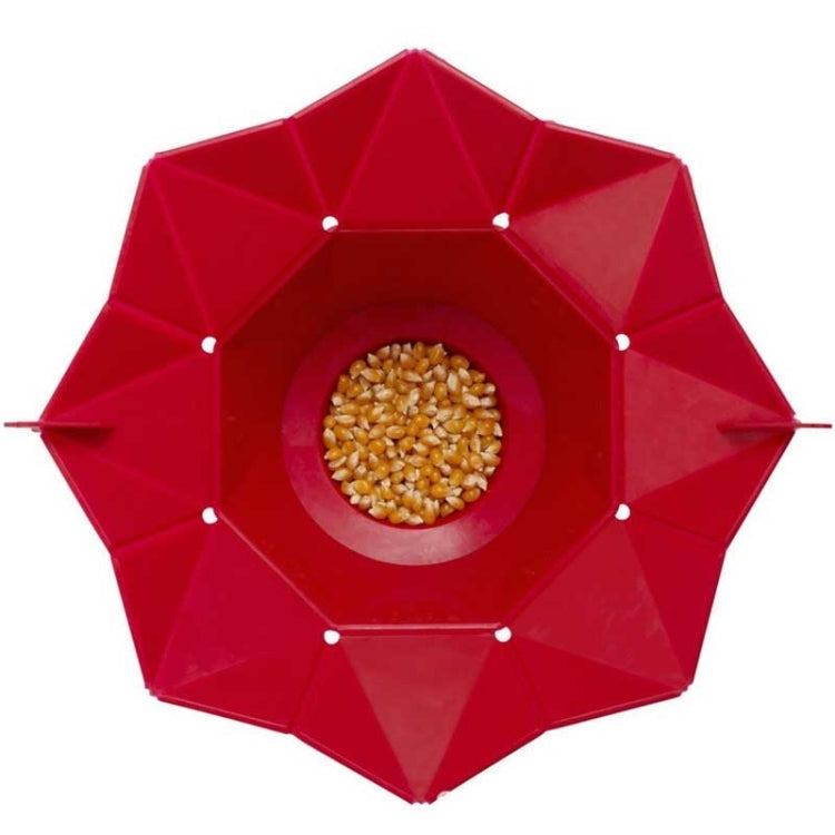 Red foldable silicone popcorn maker open with unpopped corn kernels in center