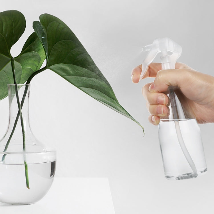 Handheld clear plastic trigger spray bottle producing mist