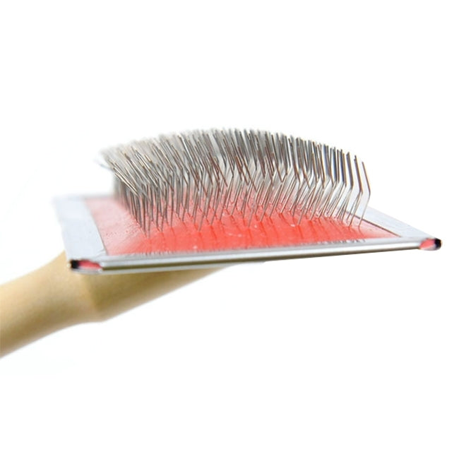 Close-up of pet brush metal needle bristles on rectangular pad with wood handle
