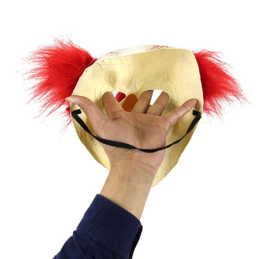 Beige bald clown latex mask with red hair tufts, held by hand (back view)