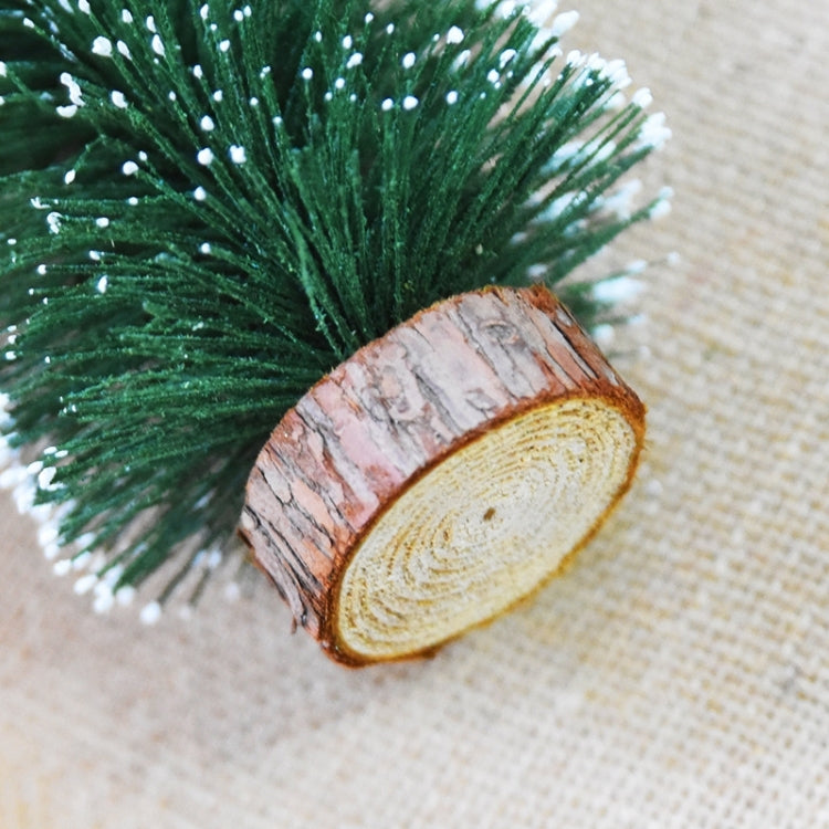 Artificial Christmas tree with green flocked branches and wood-slice base detail.