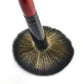 Soft powder brush with dense round bristles and dark handle with red tip