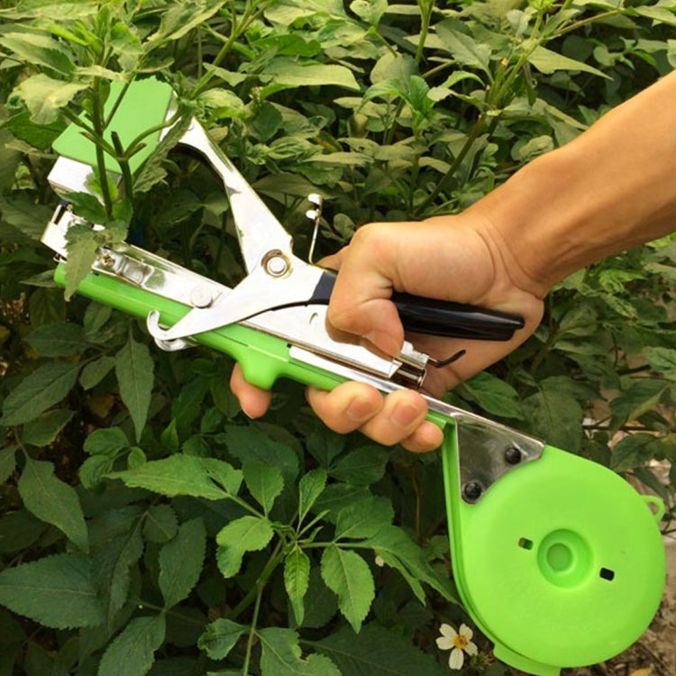 Hand-held green tape tying machine applying tape to garden stems