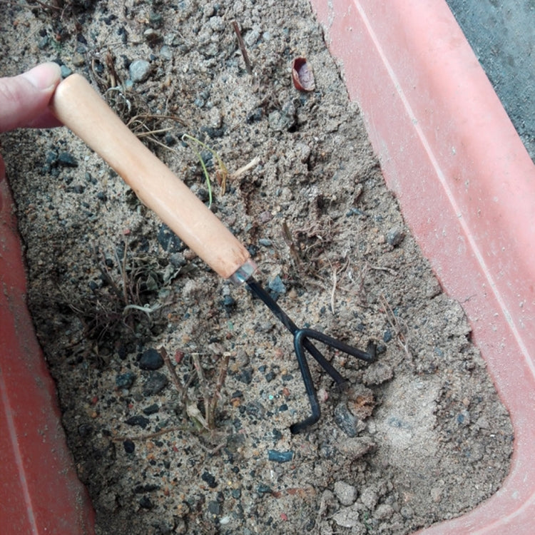 Mini garden spade with wooden handle held in soil