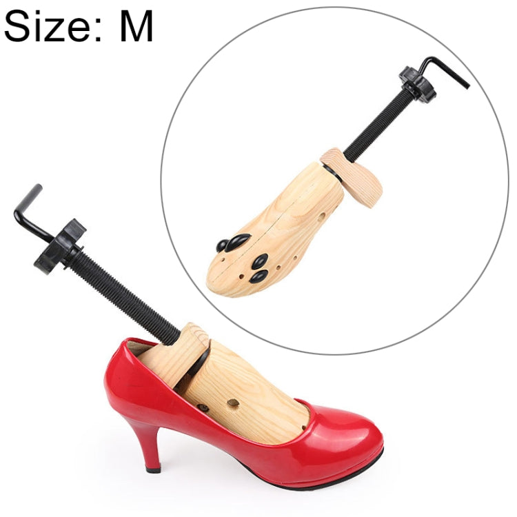 Wooden shoe stretcher shaper inserted into red high-heel pump with black screw expander