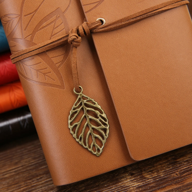 Brown leather-look travel diary notebook with embossed leaves, wrap strap, and gold leaf charm