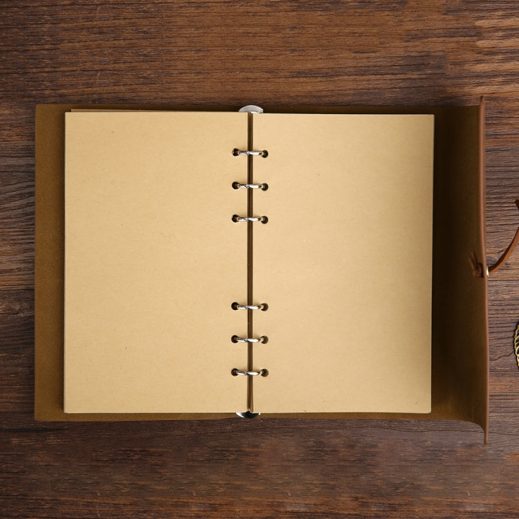 Open travel diary notebook with tan blank pages and metal ring spine on a cover