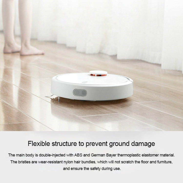 White robot vacuum on floor with visible orange main brush module