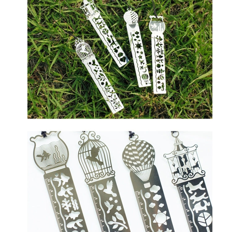 Set of silver metal bookmark rulers with decorative cutout patterns on green grass