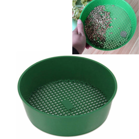 Green plastic mesh sieve, round bowl with fine grid bottom and soil sample inside