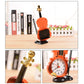 Violin-shaped alarm clock with pen holder, orange body with clock face and black stand