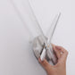 Hands attaching long white clock hands to a mirror-style silver clock center