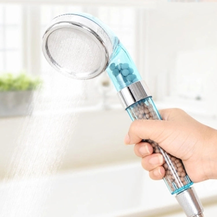 Blue handheld shower head with chrome face and translucent filter chamber, held in a hand