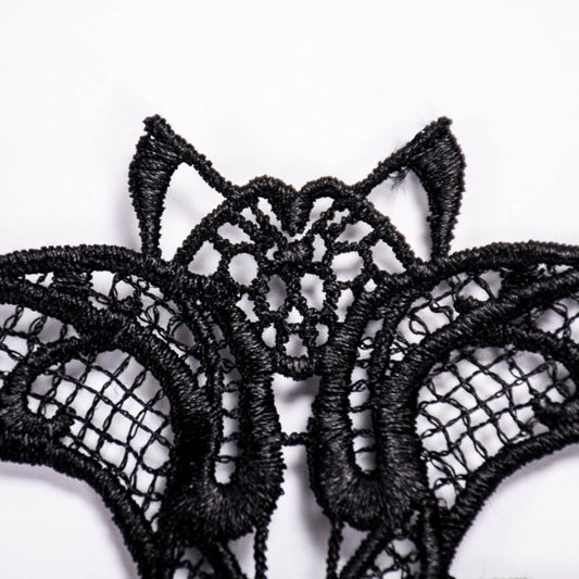 Close-up of black lace bat masquerade mask center web pattern