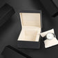 Black PU watch storage box with beige interior and watch on compartment base